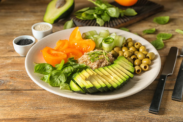 Plate with delicious healthy fresh salad on wooden table