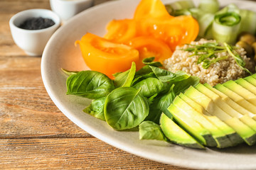 Plate with delicious healthy fresh salad on wooden table, closeup