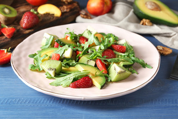 Plate with delicious healthy fresh salad on wooden table