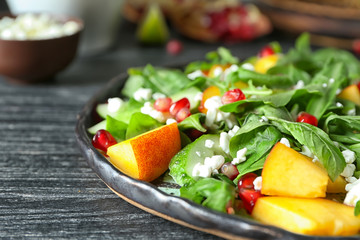 Plate with delicious healthy fresh salad on wooden table, closeup