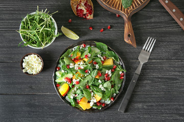 Plate with delicious healthy fresh salad on wooden table