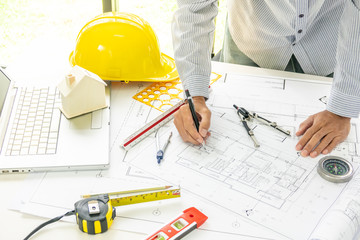 Hands of engineering man working on architect blueprint plan with architect equiptment beside at office room. Selective focus.