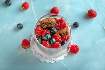 Glass with tasty raspberry dessert on color table