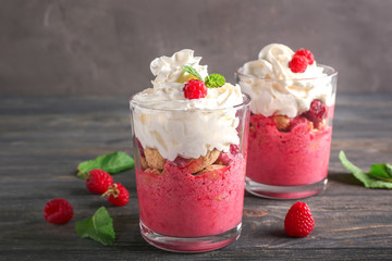 Glasses with tasty raspberry dessert on wooden table
