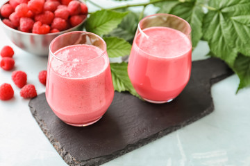 Glasses with tasty raspberry smoothie on light table