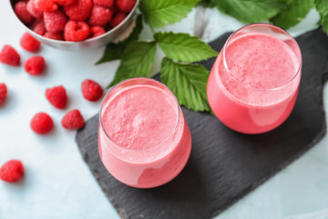 Obraz na płótnie Canvas Glasses with tasty raspberry smoothie on light table