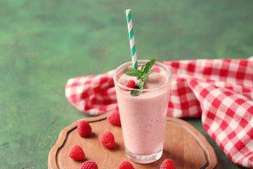 Glass with tasty raspberry smoothie on green table