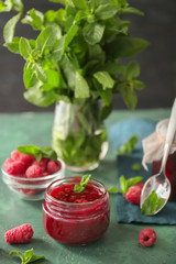Glass jar with tasty raspberry jam on table