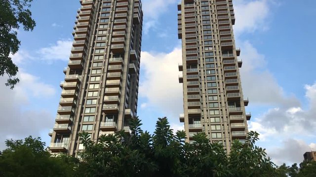 Tilt down shot of 2 apartment buildings across the Daan Park Taipei during sunset.