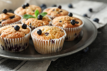 Plate with tasty blueberry muffins on table, closeup