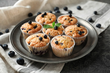 Plate with tasty blueberry muffins on table
