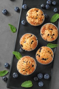 Plate with tasty blueberry muffins on table
