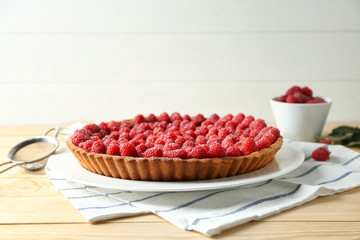 Tasty pie with fresh raspberries on wooden table