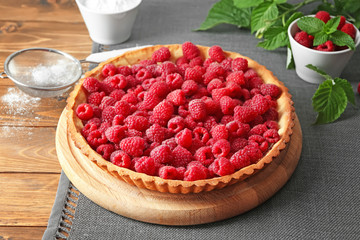 Tasty pie with fresh raspberries on wooden table