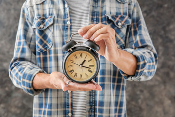 Man holding alarm clock on grey background. Time management concept