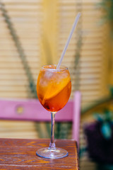 Vertical shot of Aperol spiritz cocktail which became popular in 1950s. Cold drink with ice and orange in wine glass with straw to feel fresh during hot summer