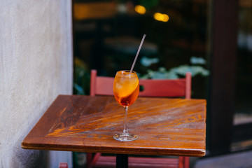 Horizontal shot of cold summer cocktail on wooden table in cafeteria. Aperol spiritz cocktail with orange and ice, served for guest. Drinks concept