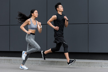 Fototapeta na wymiar side view of asian sportsman and sportswoman running at city street
