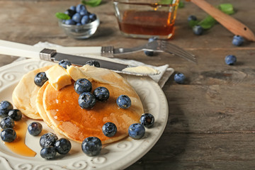 Plate with delicious pancakes and berries on wooden table