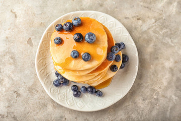 Plate with delicious pancakes and berries on light table