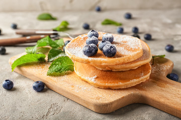 Board with delicious pancakes and berries on light table