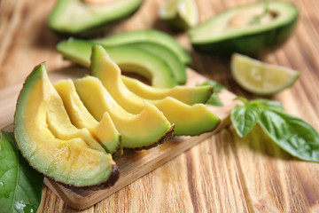 Wooden board with fresh sliced avocado on table