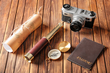 Vintage compass with spyglass, passport, map and photo camera on wooden table