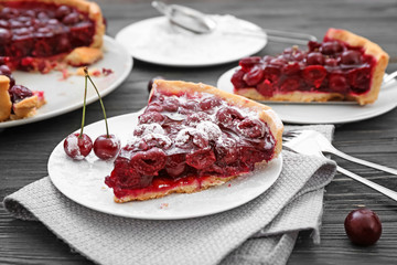Plate with piece of tasty homemade cherry pie on wooden table