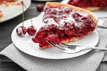 Plate with piece of tasty homemade cherry pie on wooden table, closeup
