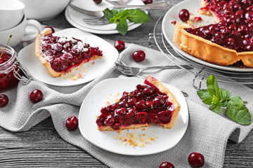 Plates with pieces of tasty homemade cherry pie on wooden table