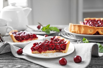 Plate with piece of tasty homemade cherry pie on wooden table