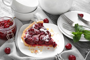 Plate with piece of tasty homemade cherry pie on wooden table