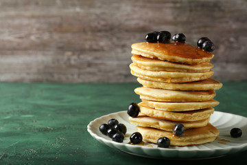 Plate with delicious pancakes and berries on green table