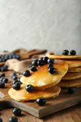 Board with delicious pancakes and berries on wooden table