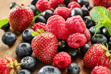 Delicious ripe berries on wooden board, closeup