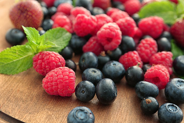 Delicious ripe berries on wooden board, closeup