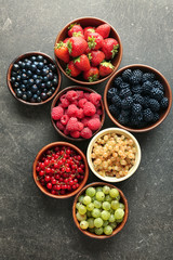 Bowls with various ripe berries on grey background, top view