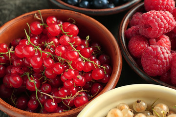 Bowls with various ripe berries on table, closeup