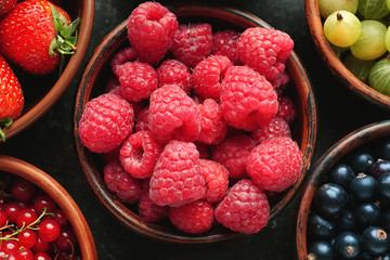 Bowls with various ripe berries on table, closeup