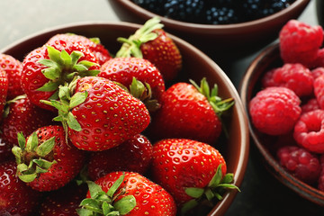 Bowls with various ripe berries on table, closeup