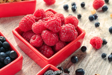 Bowl with ripe raspberries on wooden table