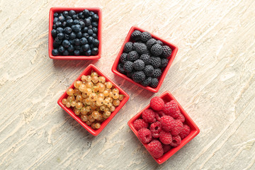 Bowls with various ripe berries on wooden background, top view