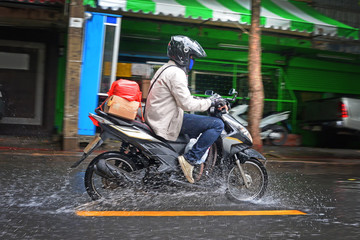 Naklejka premium Delivery Motorcycle drive through the flood on the road, flooding in Bangkok city, flooding on the road, flooding in the city