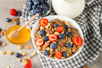 Healthy breakfast concept with oat flakes and fresh berries on rustic background. Food made of granola, muesli. Healthy banana smoothie with blackberries, muslie, strawberries, blueberries and honey.