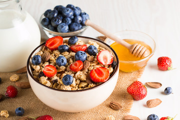 Healthy breakfast concept with oat flakes and fresh berries on rustic background. Food made of granola, muesli. Healthy banana smoothie with blackberries, muslie, strawberries, blueberries and honey.