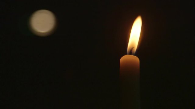 A candle buring bright in a dark room.