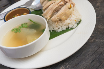 Rice, chicken, soup and sauce are in white and banana in restaurant with server for customers.front view