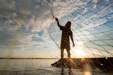 a fisherman cast a net at lake in the moring time , silhouette light