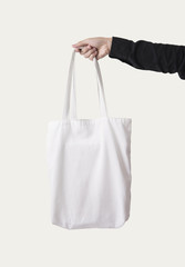 Hand holding bag canvas fabric for mockup blank template isolated on white background.
