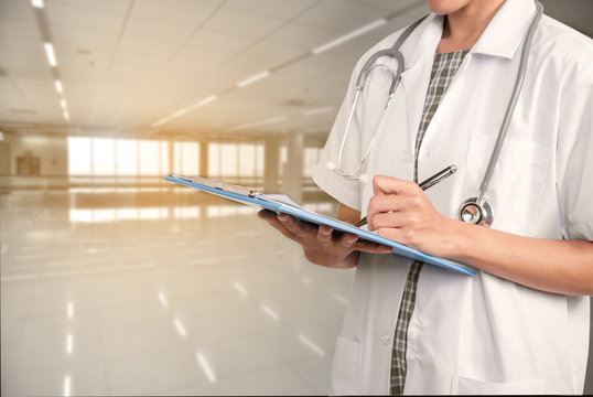 woman doctor hand holding prescription clipboard with copy space hospital background.